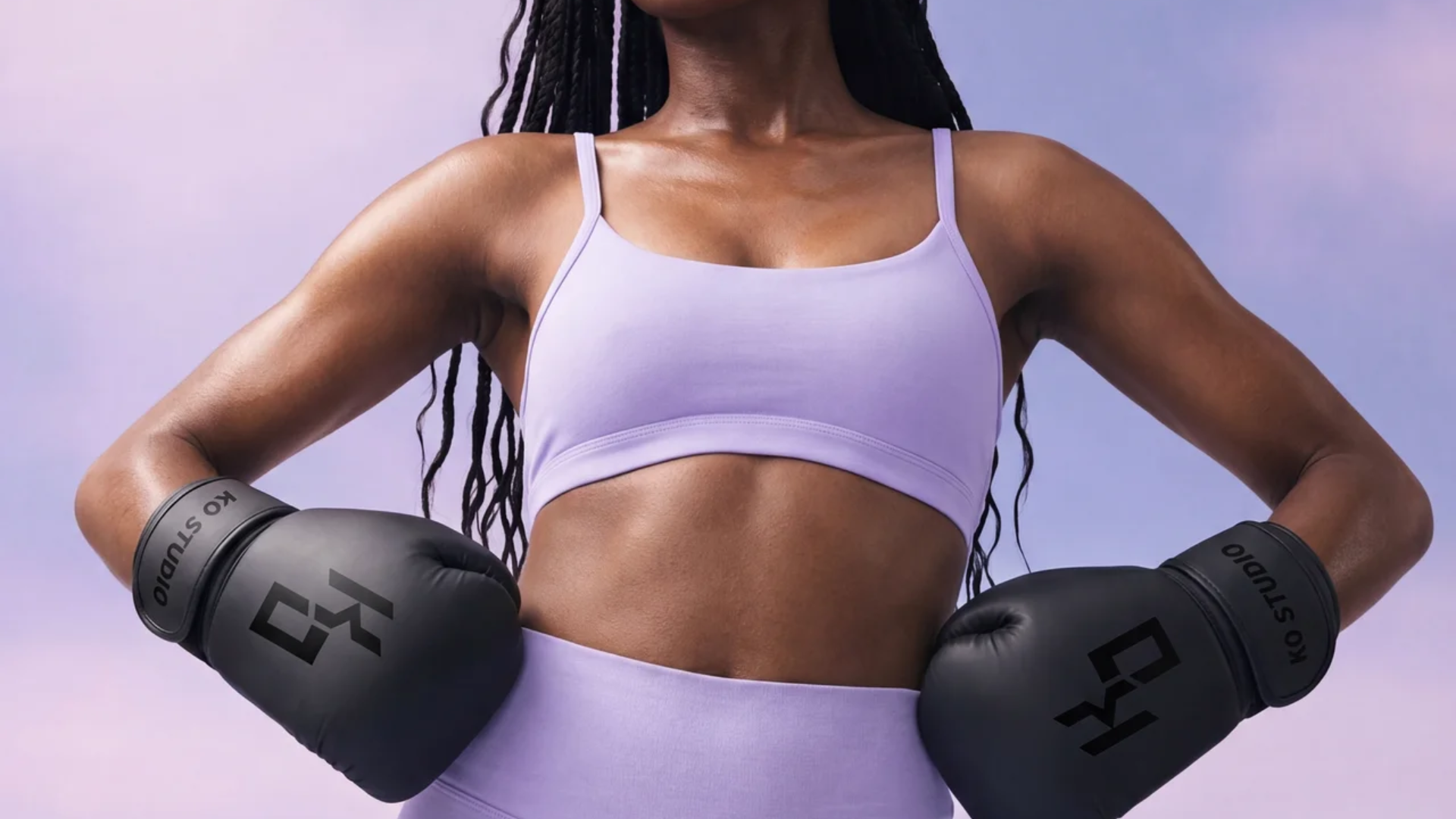 Woman in KO Studio boxing gloves training on a heavy bag, illustrating boxing for weight loss for women.
