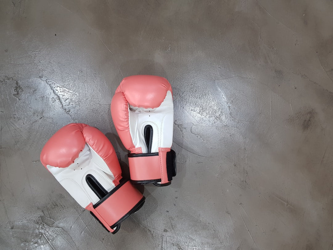 Pink and white women's boxing gloves on a concrete floor, showing wear that signals when it's time to replace your gloves.